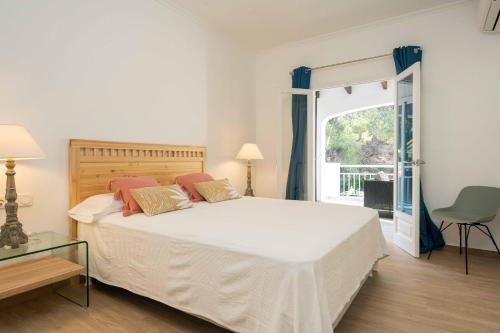 a bedroom with a large white bed and a window at Villa Arena in Es Mercadal