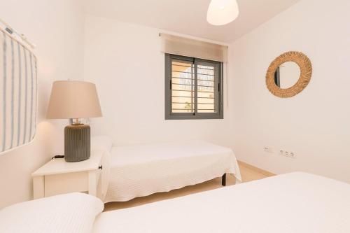 a white room with two beds and a mirror at Atardecer en Sanlúcar in Sanlúcar de Barrameda