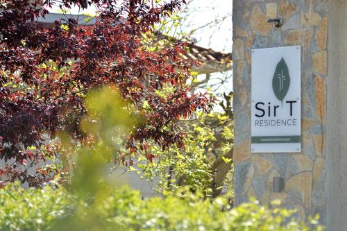 a sign on the side of a building with a tree at Sir T Residence in Flóka