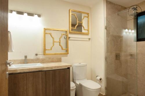 a bathroom with a toilet and a sink and a shower at Stylish Apt. w/ Rooftop, Infinity Pool & Sea View in Mazatlán