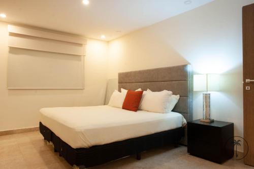 a bedroom with a bed with white sheets and red pillows at Vista a la Laguna y Amenidades Unicas in Mazatlán