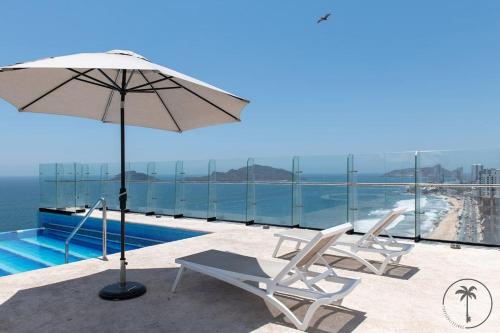 a pair of chairs and an umbrella next to a swimming pool at Vista a la Laguna y Amenidades Unicas in Mazatlán