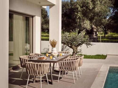 einen Tisch und Stühle auf einer Terrasse neben einem Pool in der Unterkunft SOLEIL LUXURY VILLAS in Lithakia