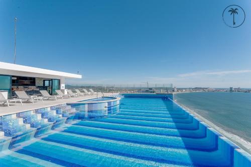 a swimming pool with chairs and the ocean at Moderno condominio con vista al mar! in Mazatlán