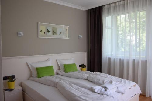 a white bedroom with a large bed with green pillows at VIP Apartments Sofia in Sofia