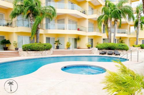 a swimming pool in front of a building with palm trees at Spacious Apartment with Pool Facing the Ocean in Mazatlán - Marina in Mazatlán