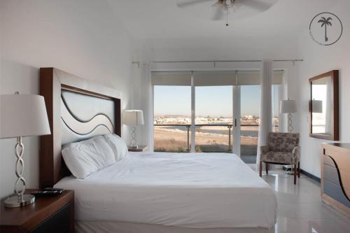Un dormitorio con una gran cama blanca y una ventana en Spacious Apartment with Pool Facing the Ocean in Mazatlán - Marina, en Mazatlán