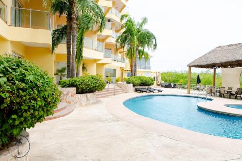 a swimming pool in front of a building with palm trees at Spacious Apartment with Pool Facing the Ocean in Mazatlán - Marina in Mazatlán