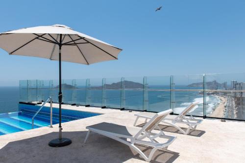 a pair of chairs and an umbrella next to a swimming pool at Nuevo Departamento en el Malecón! in Mazatlán