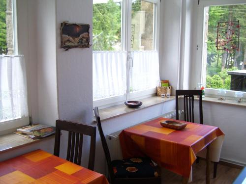 ein Esszimmer mit einem Tisch, 2 Stühlen und Fenstern in der Unterkunft Heine Apartment-Friedegerns Fewo in Schierke
