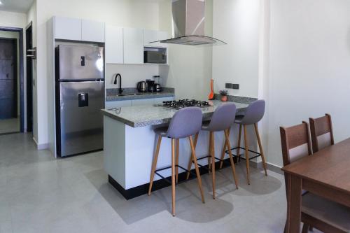 a kitchen with a stove and a counter with stools at Spacious family apartment in Mazatlán in Isla Venados