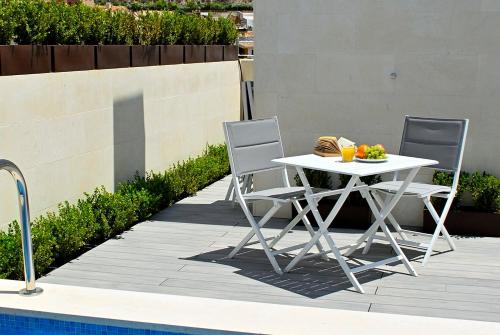a white table and two chairs next to a pool at Holihome Rambla 24 in Alicante