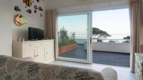 een woonkamer met een bank en een glazen schuifdeur bij Welcomely - La Casa Sul Mare in Cala Liberotto