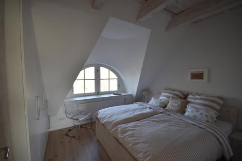 a white bedroom with a bed and a window at Hoheluft am Wittensee Apt 2 in Groß Wittensee