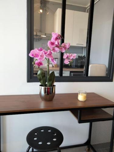 une table avec un vase de fleurs roses sur elle dans l'établissement Studio chaleureux Caen, à Caen