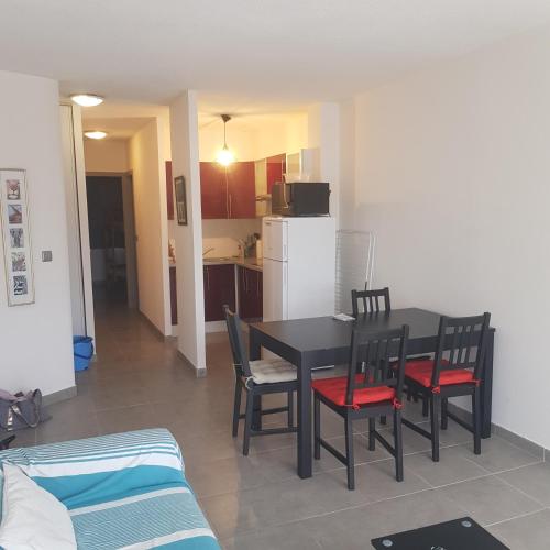 une table de salle à manger avec des chaises et une cuisine dans l'établissement Lacanau Océan- Bel appart- 2 Ch, à Lacanau-Océan