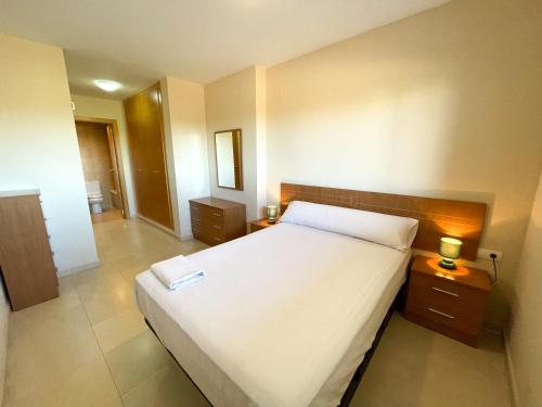 1 dormitorio con 1 cama blanca grande y 2 lámparas en Apartamentos Terrazas al Mar 3000, en Oropesa del Mar