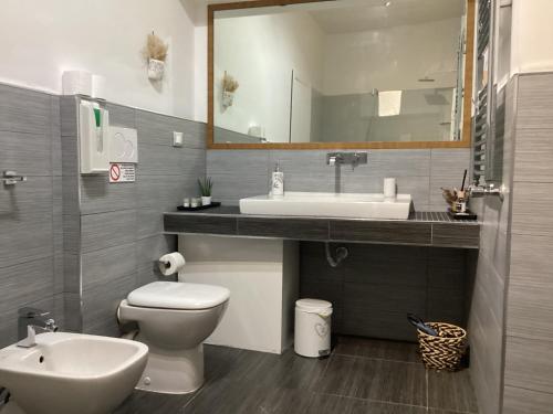 een badkamer met een wastafel, een toilet en een spiegel bij Romerooms Cola di Rienzo in Rome