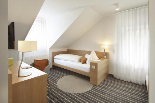 a bedroom with a bed and a table with a lamp at Hotel Hiller in Abstatt in Abstatt