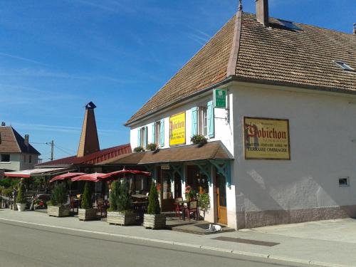 un bâtiment avec des tables et des parasols dans une rue dans l'établissement Hotel Restaurant Robichon, à Loray
