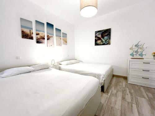 Habitación con 2 camas, paredes blancas y suelo de madera. en 3 bedrooms with private parking By Canary365, en Las Palmas de Gran Canaria