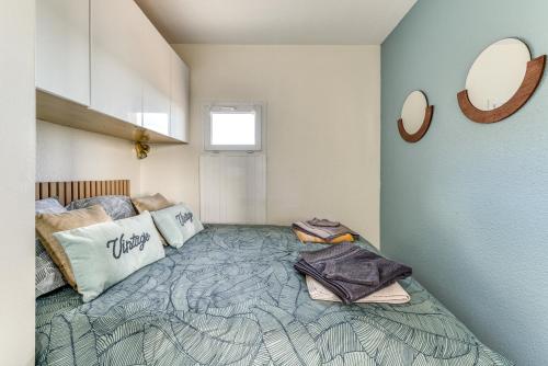 Schlafzimmer mit einem Bett und einem Wandspiegel in der Unterkunft T2 Miami Beach in Narbonne-Plage