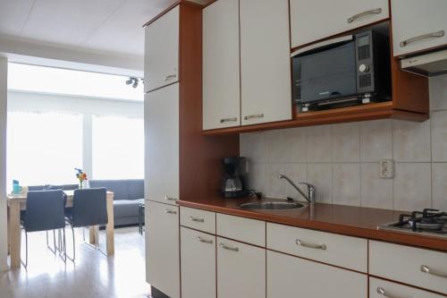 a kitchen with white cabinets and a microwave and a table at Zeezand in Egmond aan Zee