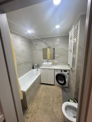 a bathroom with a tub sink and a washing machine at Lux Apartmen Zona Circ in Chişinău