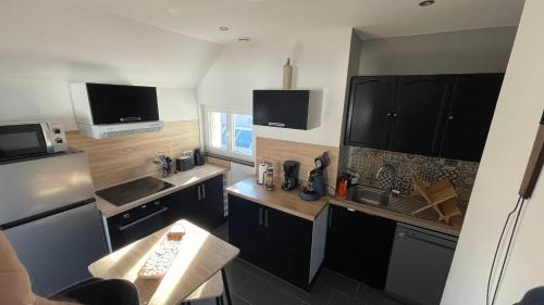 a kitchen with black and white cabinets and a sink at les Calimottes in Sangatte