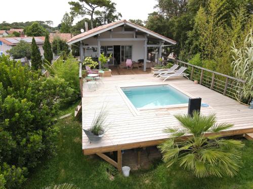 eine Holzterrasse mit einem Pool und einem Haus in der Unterkunft Villa OHANA pour 8 personnes avec piscine et cuisine d'été. Wifi gratuit in Capbreton