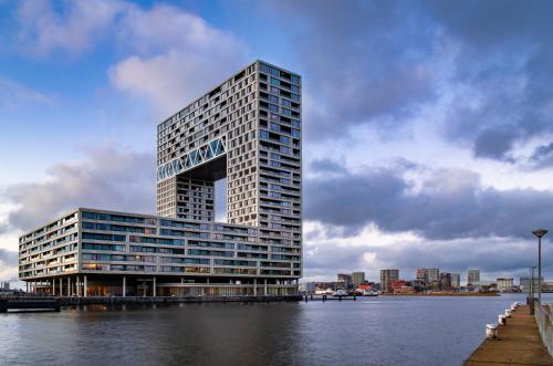 ein hohes Gebäude neben einem Wasserkörper in der Unterkunft Eric Vökel Boutique Apartments - Riverfront Suites in Amsterdam