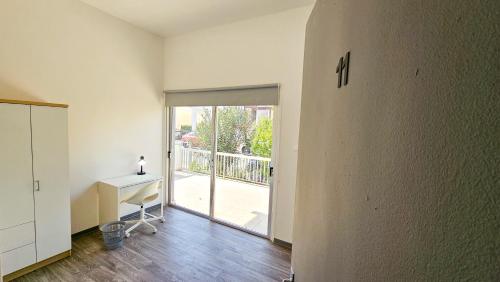 een lege kamer met een bureau en een glazen schuifdeur bij The Lemon Tree Hostel in Larnaka