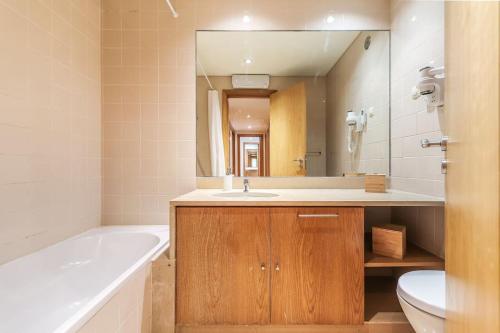 La salle de bains est pourvue d'une baignoire, d'un lavabo et d'un miroir. dans l'établissement Vita Portucale ! Expo Deluxe with Terrace, à Lisbonne