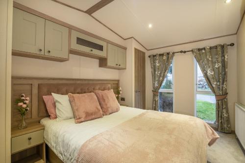 ein Schlafzimmer mit einem großen Bett und einem Fenster in der Unterkunft QUEEN V - Luxury Caravan - 2Bed - Seton Sands in Port Seton