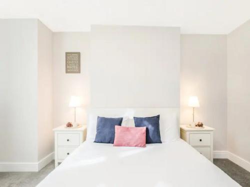 una camera da letto con un letto bianco con cuscini blu e rosa di Pass The Keys Basement Hideaway near Acton Main Line Your Peaceful Escape with London at Your Fingertips a Londra