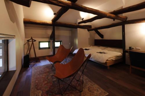 a bedroom with a bed and two chairs in it at Satoyama Jujo The House in Minami Uonuma