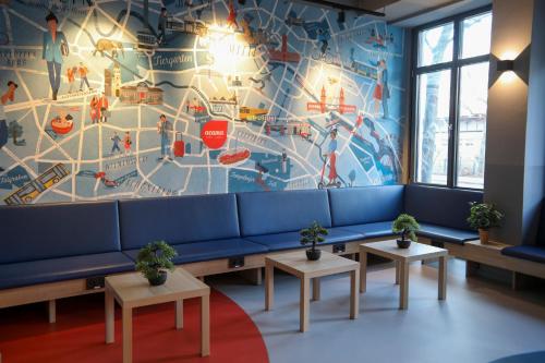 a waiting room with a blue couch and a mural at acama Hotel & Hostel Kreuzberg in Berlin