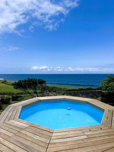 a swimming pool with the ocean in the background at Caldeira Guesthouse in Fajã da Caldeira de Santo Cristo