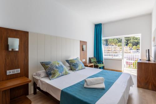 um quarto com uma cama grande e um cobertor azul em Hostal Neptuno em Paguera