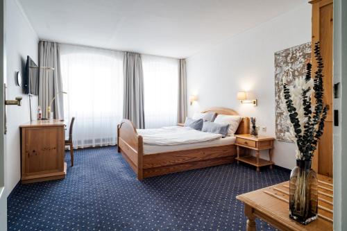 a hotel room with a bed and a vase of flowers at Hotel Goldener Hirsch in Kaufbeuren