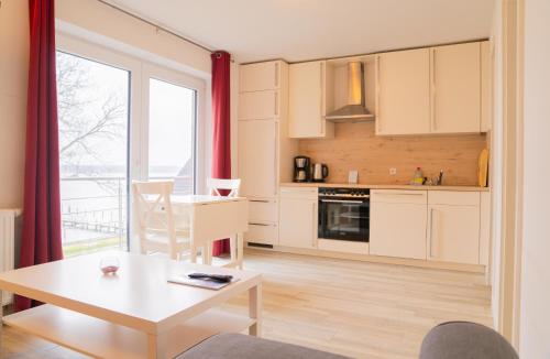 Rabenkirchen-Faulück的住宿－Schleiblick App 18，厨房以及带桌子和窗户的用餐室。