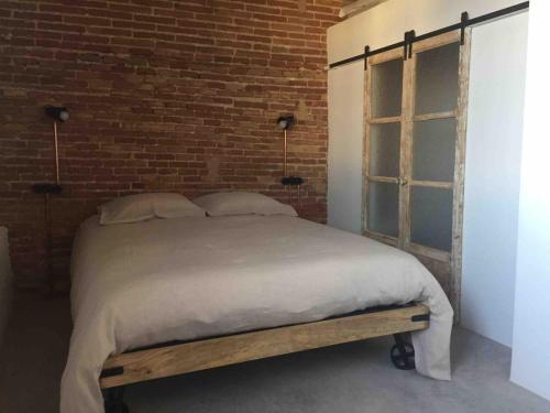 バルセロナにあるCosy & Bright Apartment Near Ramblasのレンガの壁のドミトリールームのベッド1台分です。