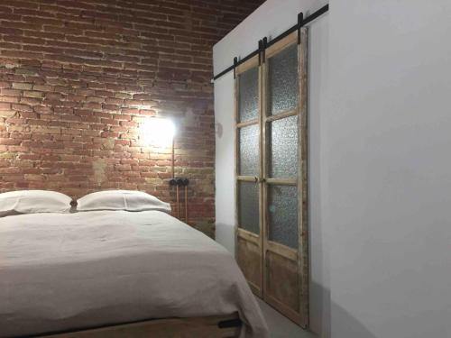 a bedroom with a bed and a brick wall at Cosy & Bright Apartment Near Ramblas in Barcelona