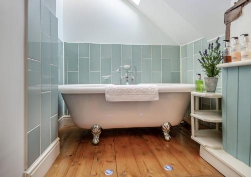 uma banheira na casa de banho com azulejos verdes em Alde Cottage em Friston