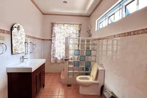 a bathroom with a toilet and a sink and a window at Panglao Cove Resort_Main House in Dauis