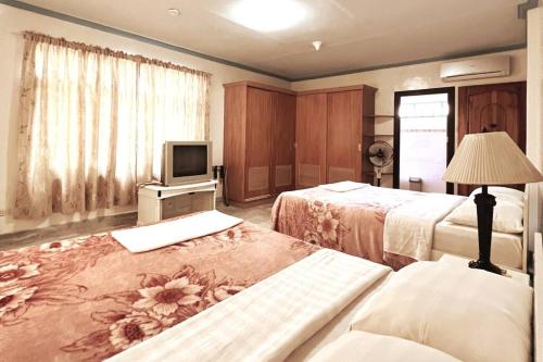 a hotel room with two beds and a television at Panglao Cove Resort_Main House in Dauis