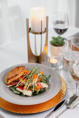 a plate of food on a table with wine glasses at Pałac Wojanów in Wojanów