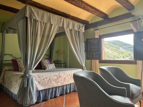 1 Schlafzimmer mit einem Himmelbett und 2 Stühlen in der Unterkunft Casa de Santiago in Albarracín