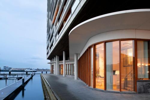 a building with large windows next to a body of water at Eric Vökel Boutique Apartments - Riverfront Suites in Amsterdam