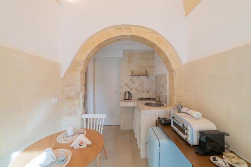 a kitchen with an archway and a table with a toaster at Fjore di Lecce, camere & caffè in Lecce